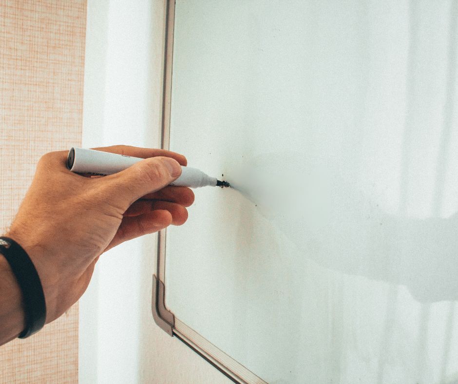 left-handed writer writing on a whiteboard