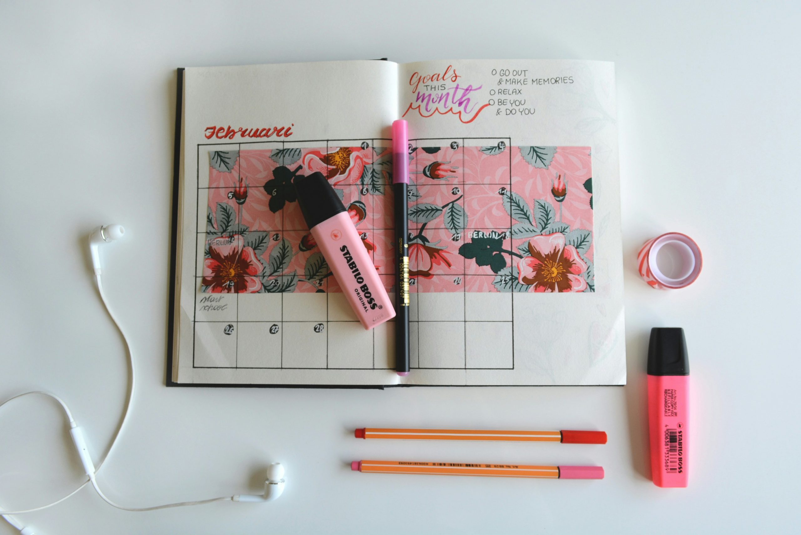 bullet journal with highligher, pens, headphones