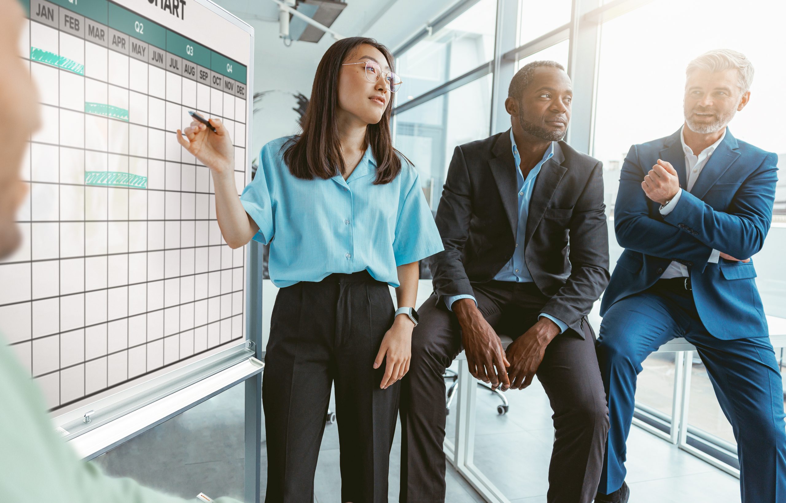 woman and two men in corporate gear in front of custom whiteboard